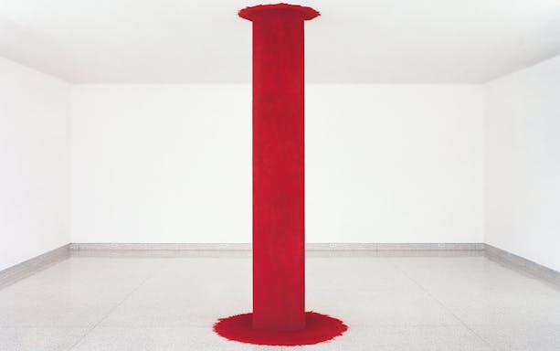 Red pillar installation by Anish Kapoor in a white gallery space.