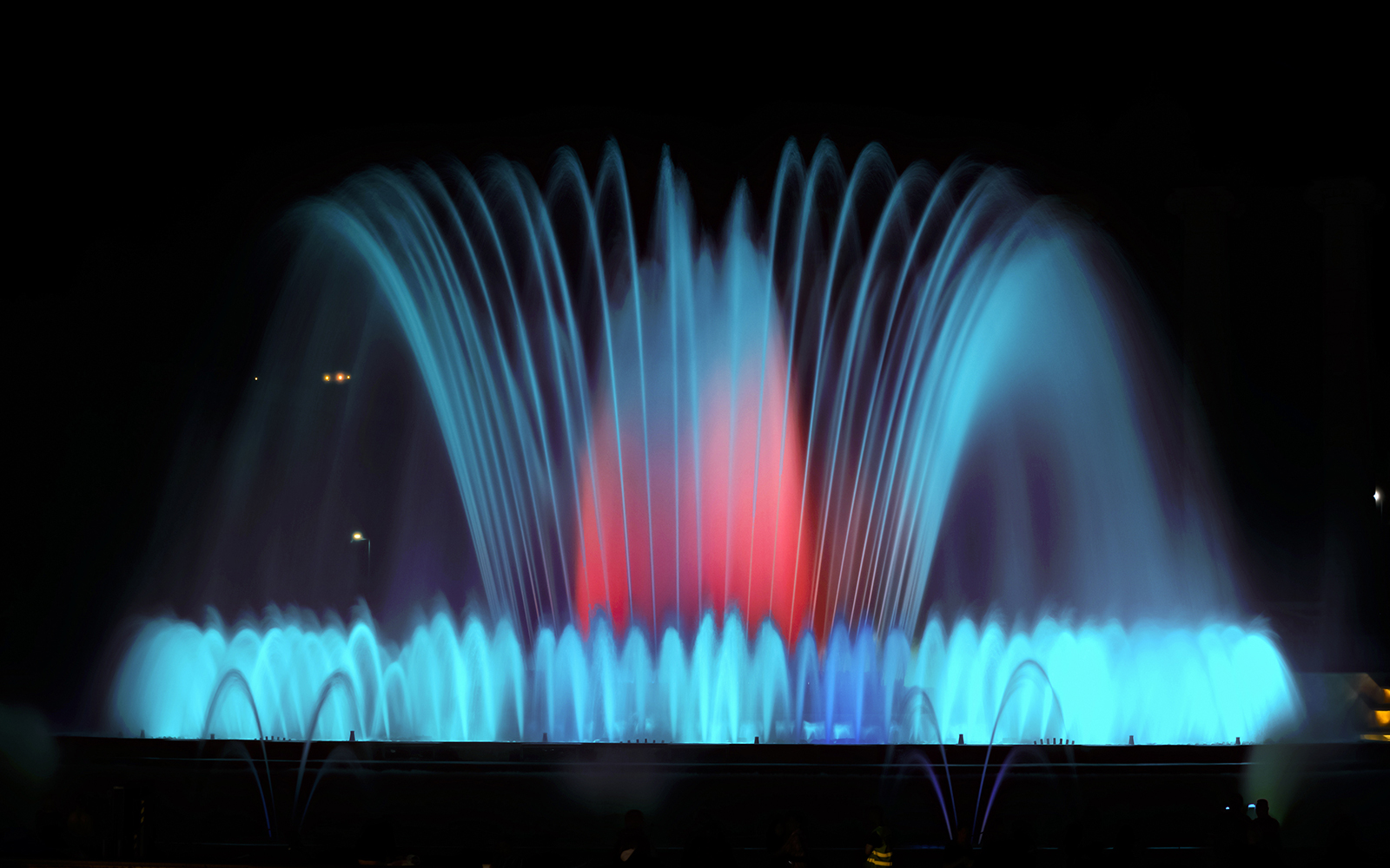 Montjuic Fountain illuminated at night in Barcelona, showcasing vibrant water displays.