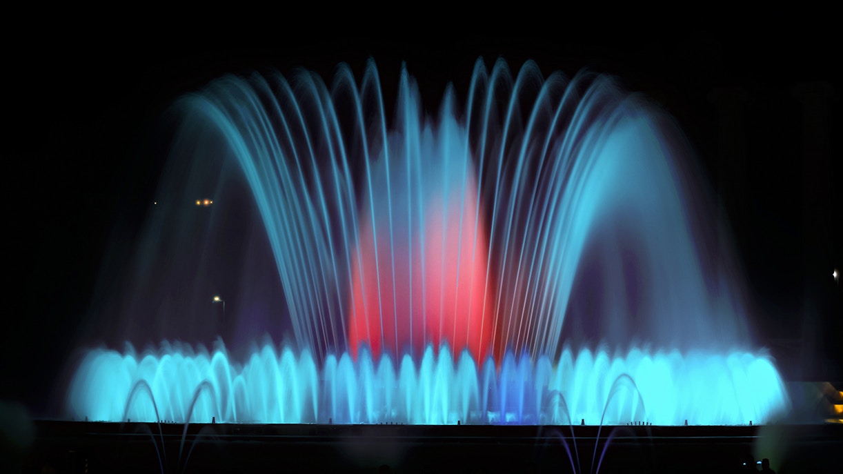 Montjuic Fountain illuminated at night in Barcelona, showcasing vibrant water displays.