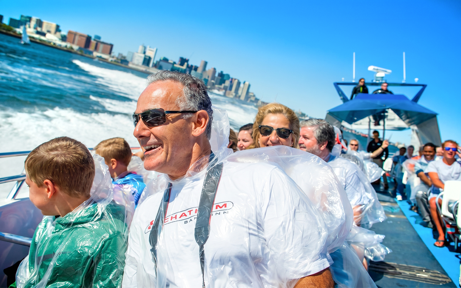 Passengers enjoying the CODZILLA thrill-boat ride in Boston with city skyline in background.