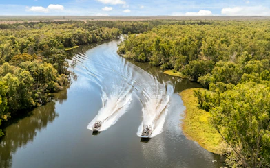 Airboats cruising along the Finniss River surrounded by lush greenery.