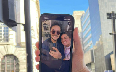Smartphone displaying a selfie of two people in Liverpool during a city exploration game.