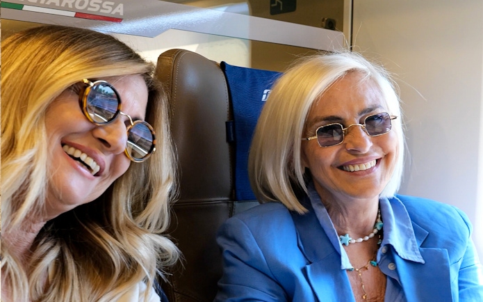 Two women smiling on an Italian train journey.