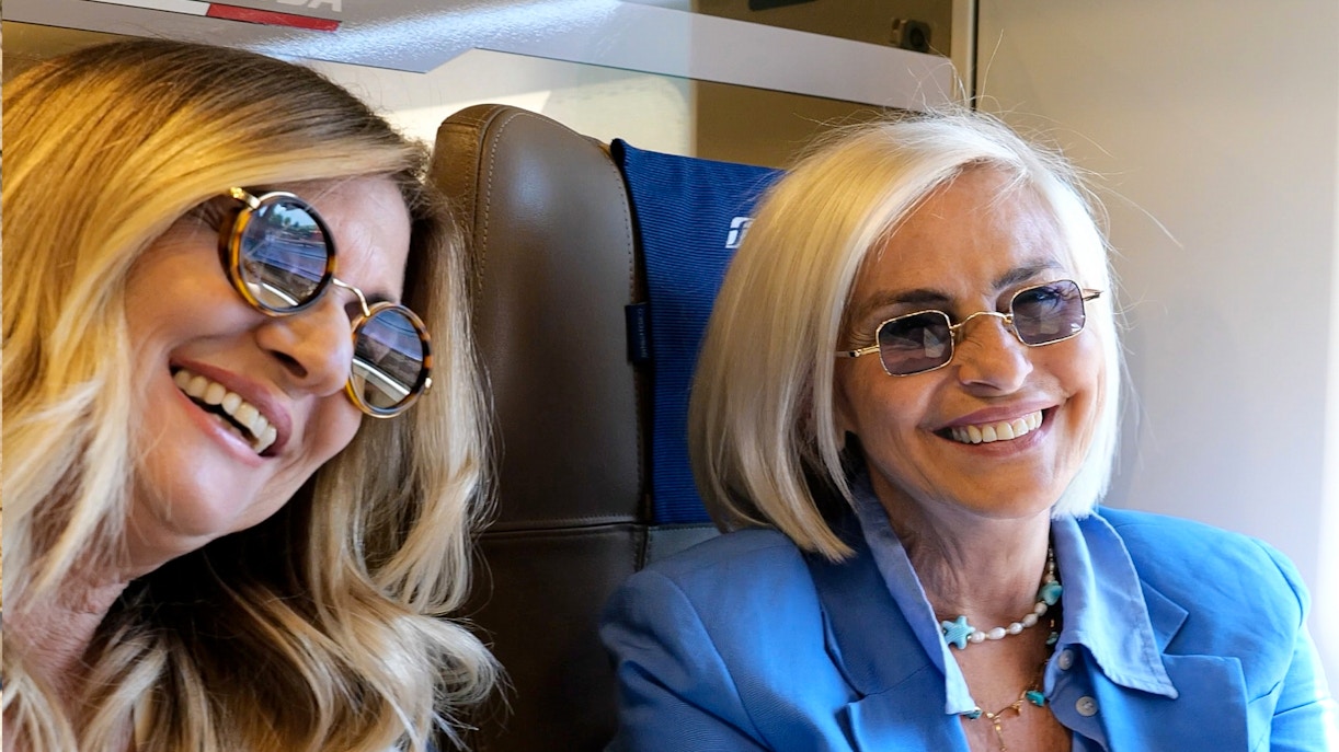 Two women smiling on an Italian train journey.