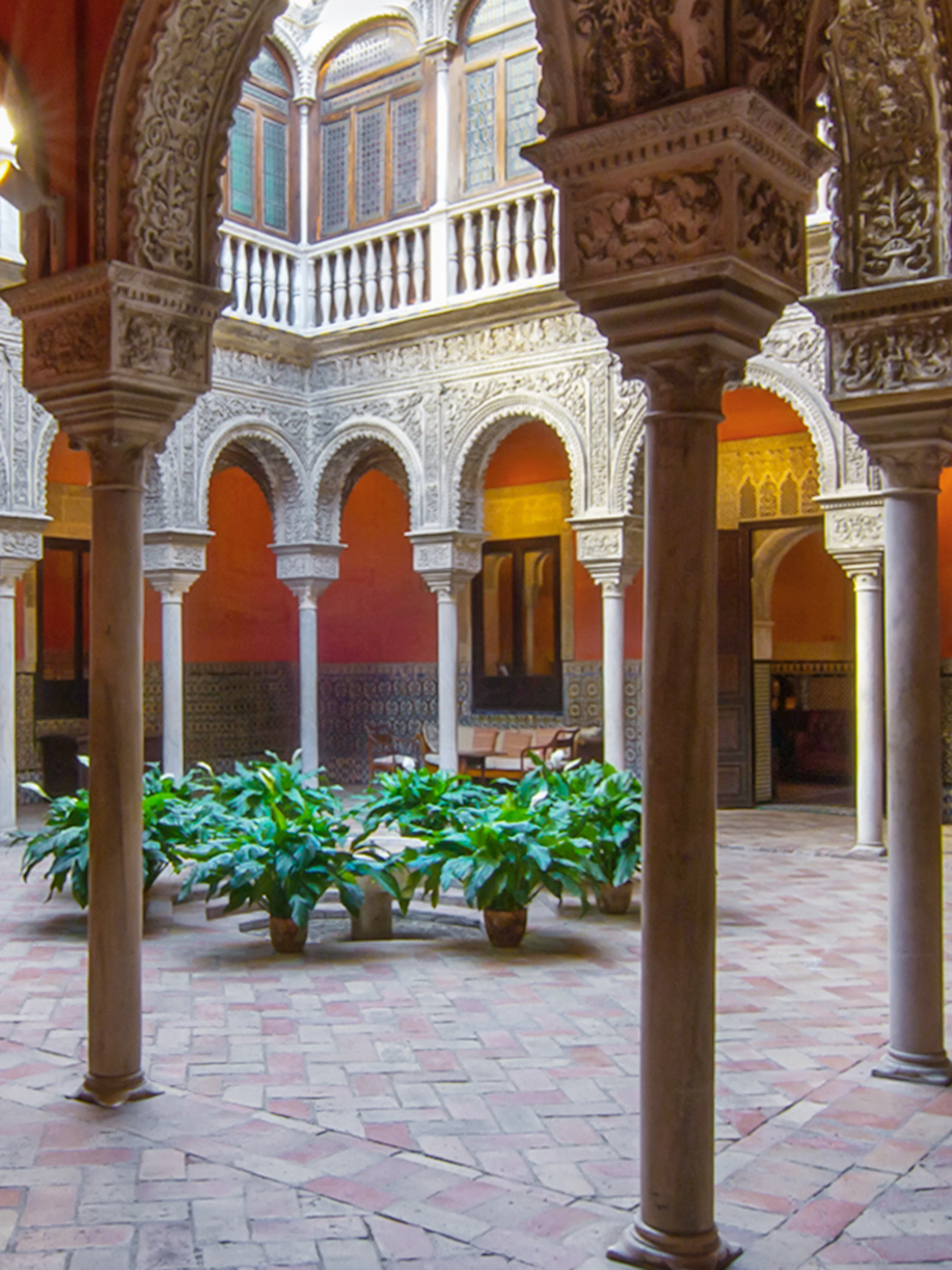 Casa de Salinas courtyard with ornate arches and tiled walls in Seville, Spain.