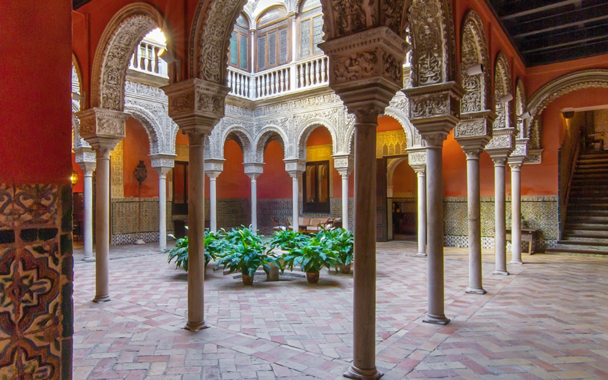 Casa de Salinas courtyard with ornate arches and tiled walls in Seville, Spain.