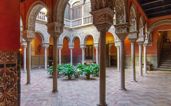 Casa de Salinas courtyard with ornate arches and tiled walls in Seville, Spain.