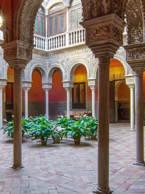 Casa de Salinas courtyard with ornate arches and tiled walls in Seville, Spain.