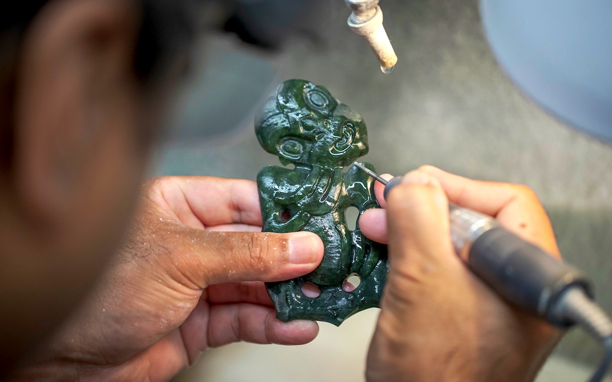 Carving a traditional Māori greenstone pendant at Te Puia, New Zealand.