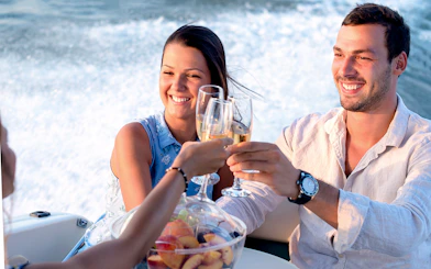 Guests toasting on a Santorini catamaran cruise with fruit platter.