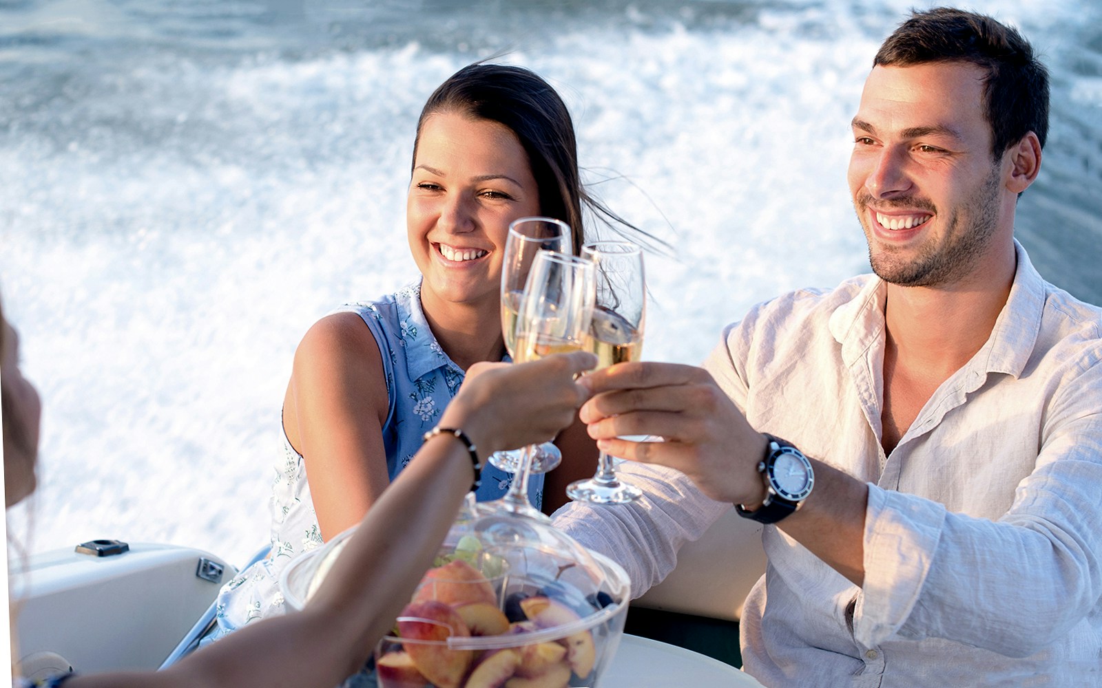 Catamaran sailing in Santorini's caldera with passengers enjoying a meal and drinks.