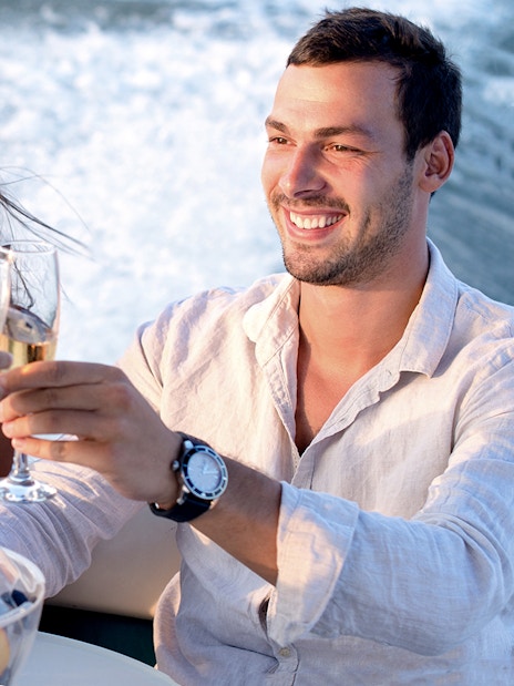 Guests toasting on a Santorini catamaran cruise with fruit platter.