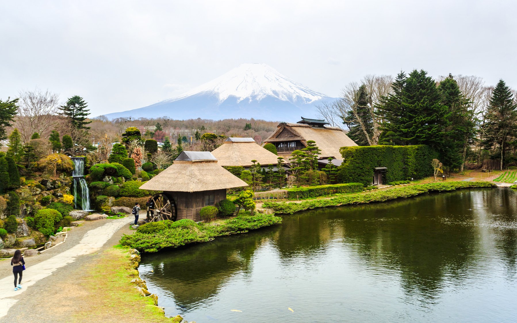 Traditional Japanese village with thatched roofs near Lake Kawaguchiko, Mt. Fuji in the background.