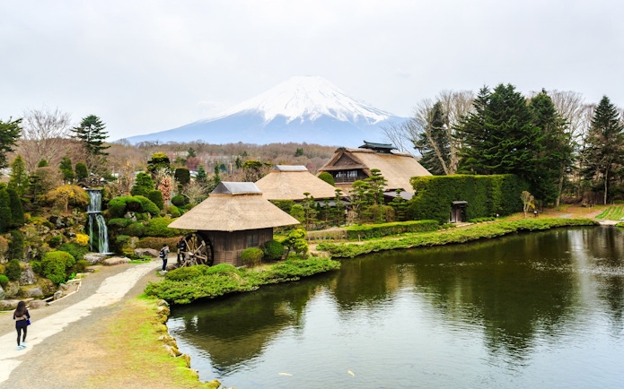 Traditional Japanese village with thatched roofs near Lake Kawaguchiko, Mt. Fuji in the background.