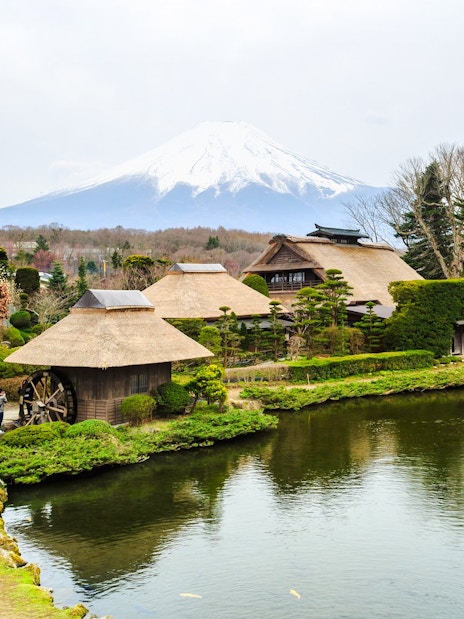 Traditional Japanese village with thatched roofs near Lake Kawaguchiko, Mt. Fuji in the background.