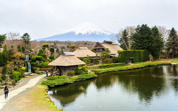 Traditional Japanese village with thatched roofs near Lake Kawaguchiko, Mt. Fuji in the background.