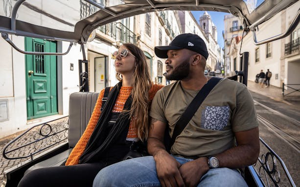 Couple enjoying a private electric tuk tuk tour through a historic European city street.