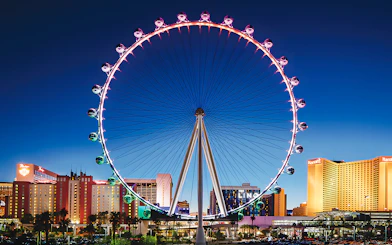 High Roller Wheel illuminated at night, Las Vegas skyline in background.