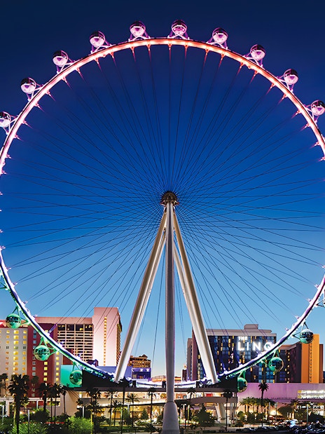 High Roller Wheel illuminated at night, Las Vegas skyline in background.