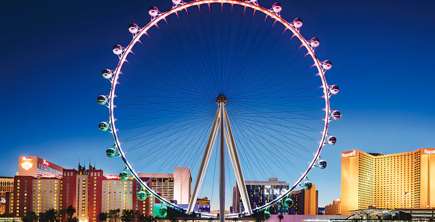 High Roller Wheel illuminated at night, Las Vegas skyline in background.