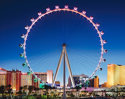 High Roller Wheel illuminated at night, Las Vegas skyline in background.