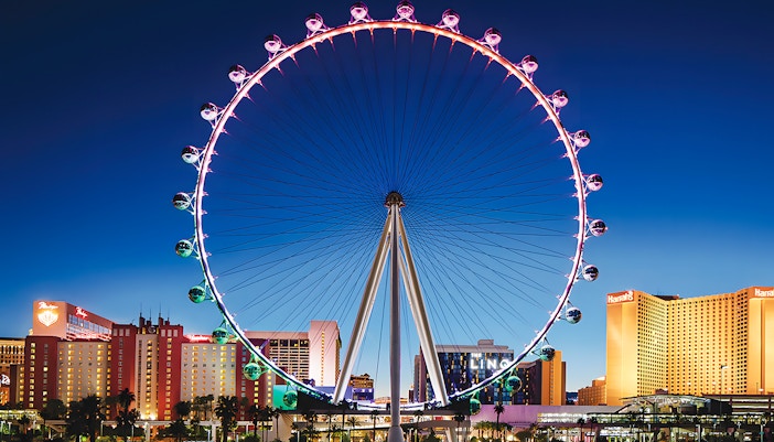 High Roller Wheel illuminated at night, Las Vegas skyline in background.