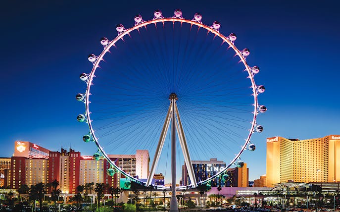 High Roller Wheel illuminated at night, Las Vegas skyline in background.