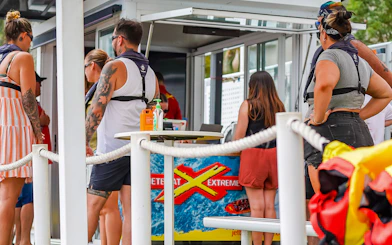 People preparing for the Ultimate Jet Boat Ride at a waterfront kiosk.