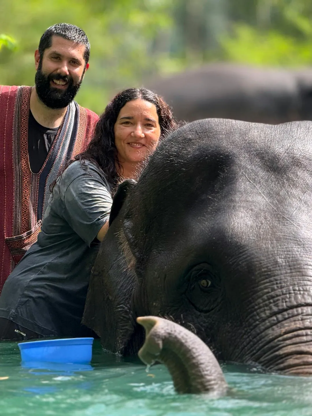 Couple interacting with an elephant during a bathing experience at Phuket Elephant Care Sanctuary.