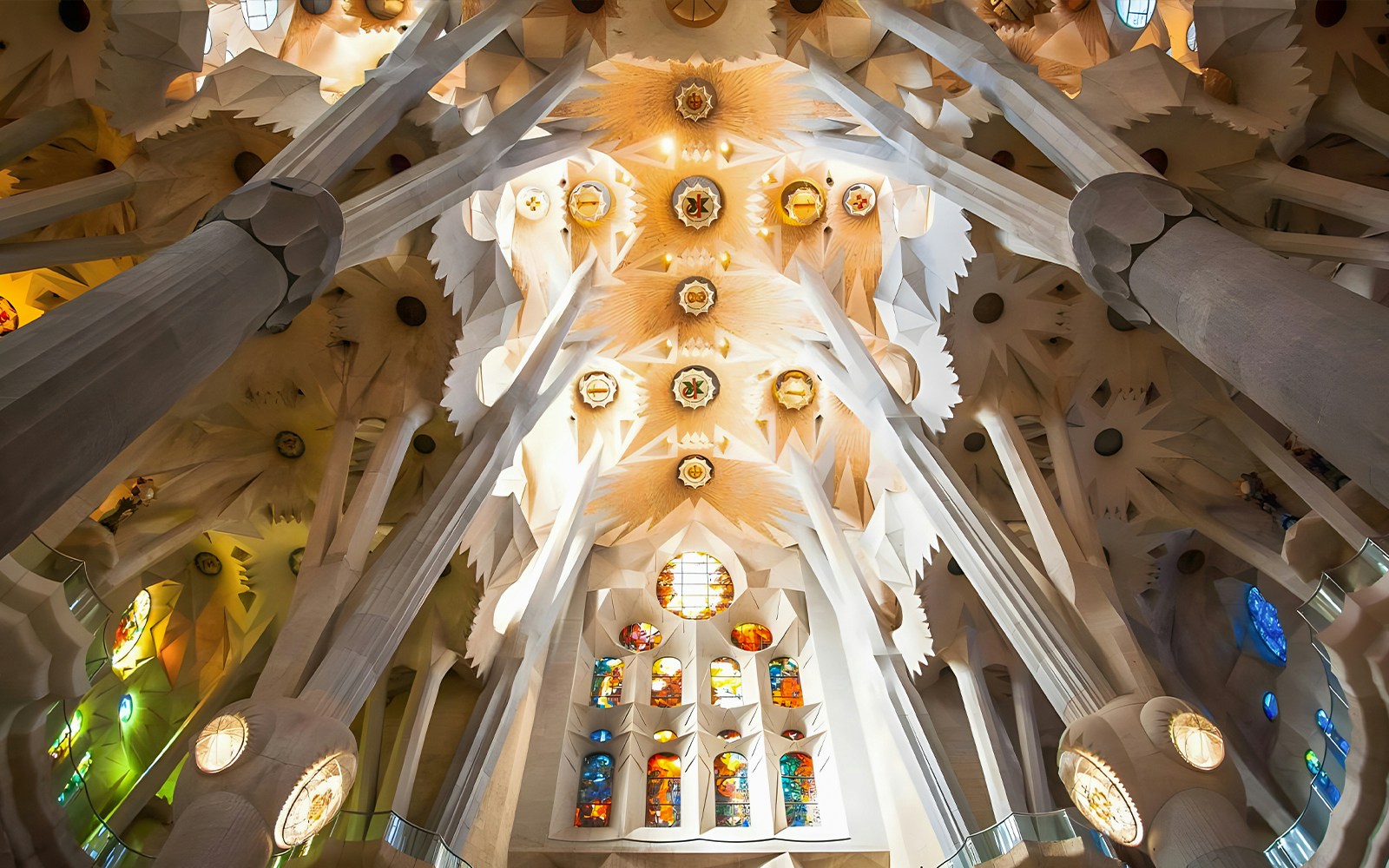 Sagrada Familia ceiling with intricate decor and stained glass windows in Barcelona.