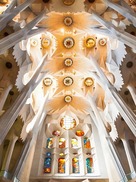 Sagrada Familia ceiling with intricate decor and stained glass windows in Barcelona.