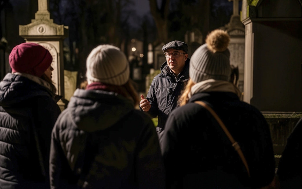 Tour guide leading a haunted cemetery bus tour at night.