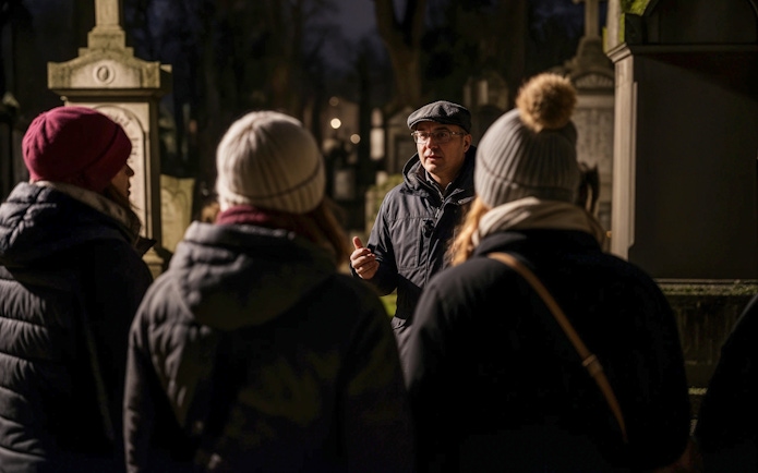 Tour guide leading a haunted cemetery bus tour at night.