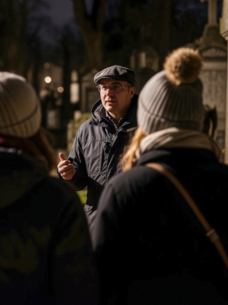 Tour guide leading a haunted cemetery bus tour at night.