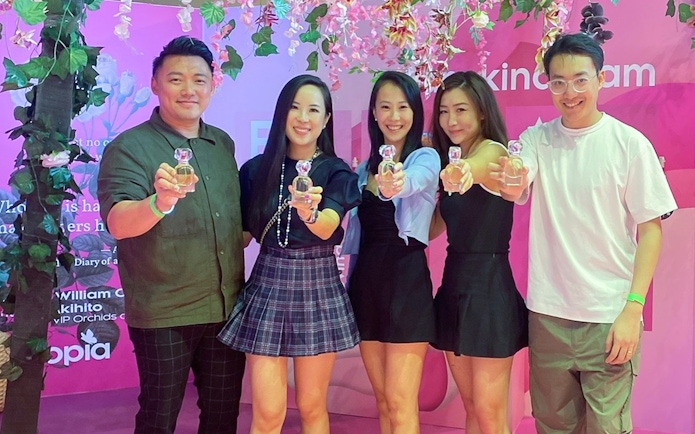Group holding perfume bottles at Scentopia Sentosa exhibit.