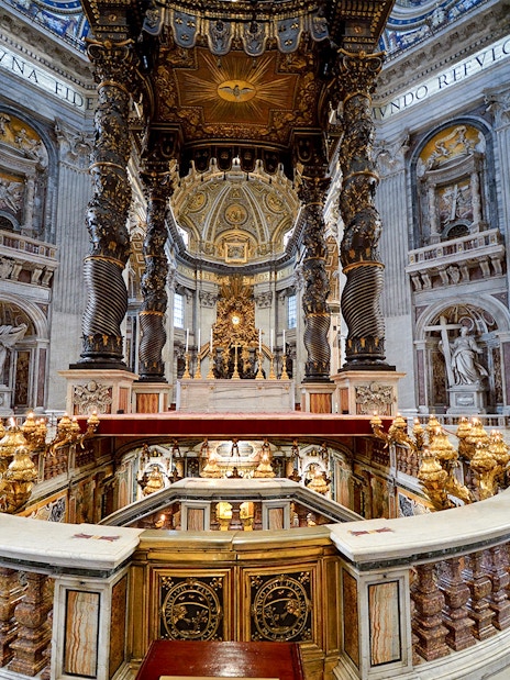 St. Peter's Basilica interior with ornate altar and spiral columns in Vatican City.