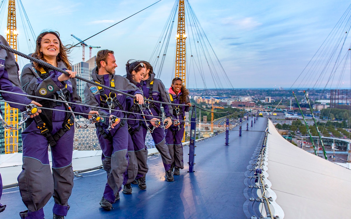 Guests climbing the O2 Arena roof at twilight in London.