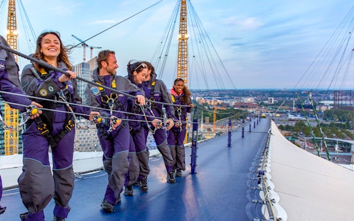 Guests climbing the O2 Arena roof at twilight in London.
