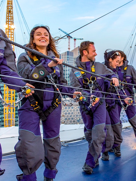 Guests climbing the O2 Arena roof at twilight in London.