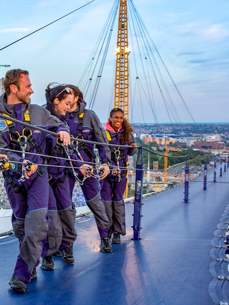Guests climbing the O2 Arena roof at twilight in London.