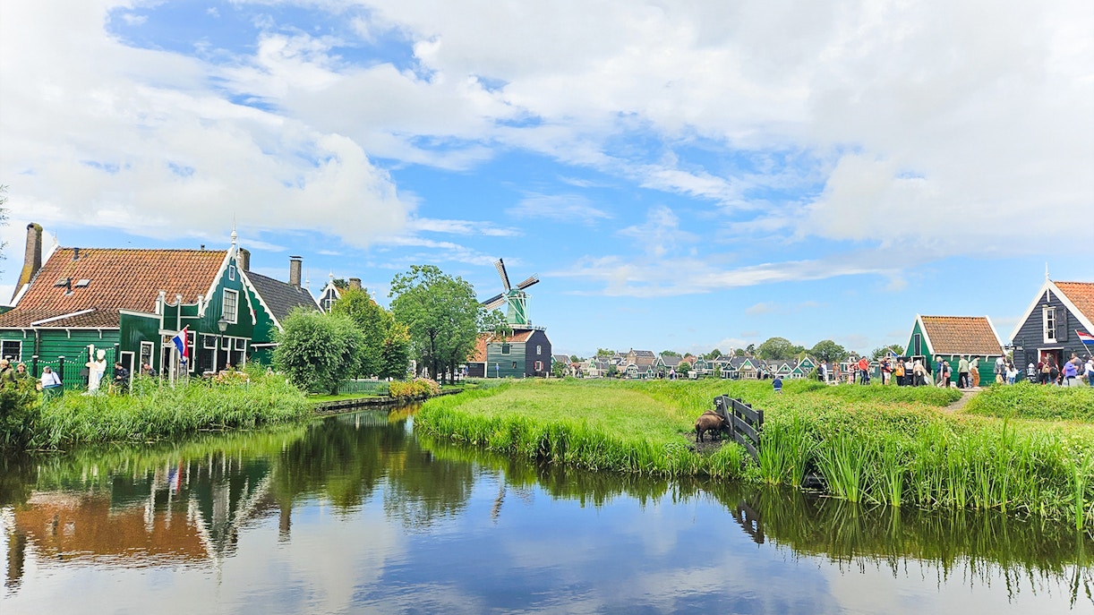 Windmill and traditional houses by a canal in Zaanse Schans, Netherlands.