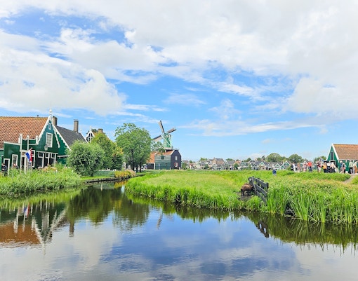 Windmill and traditional houses by a canal in Zaanse Schans, Netherlands.