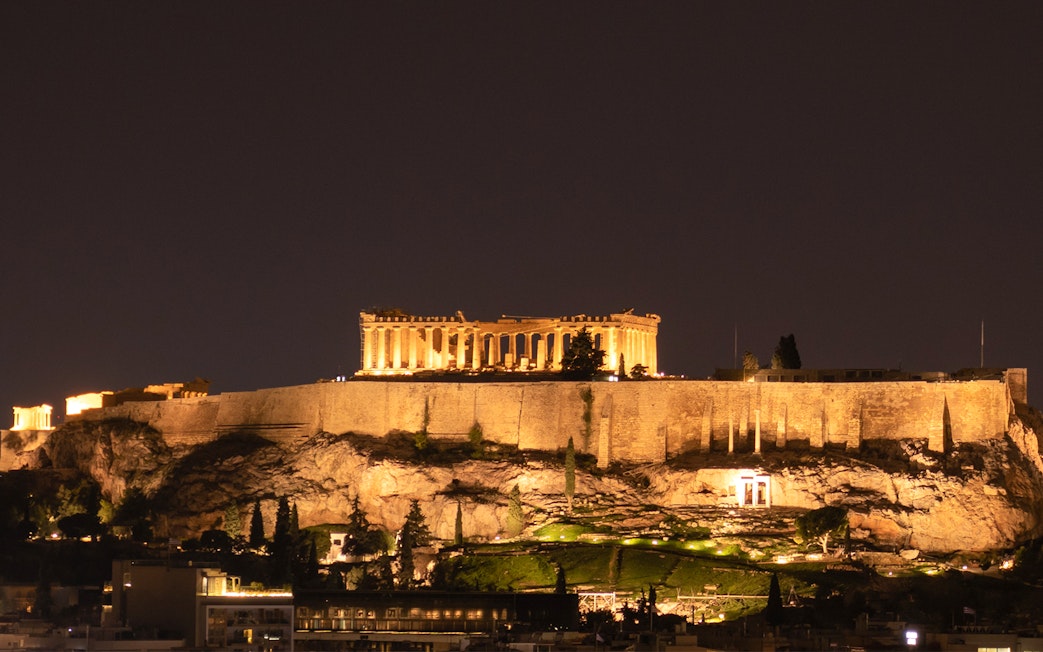 Acropolis illuminated at night on a hill in Athens, Greece.