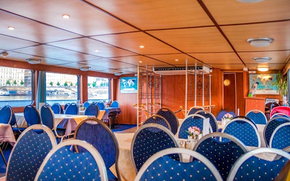 Interior of a Prague sightseeing boat with dining tables and river view.