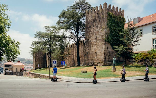 Tourists on Segways with guide near medieval wall in Porto.