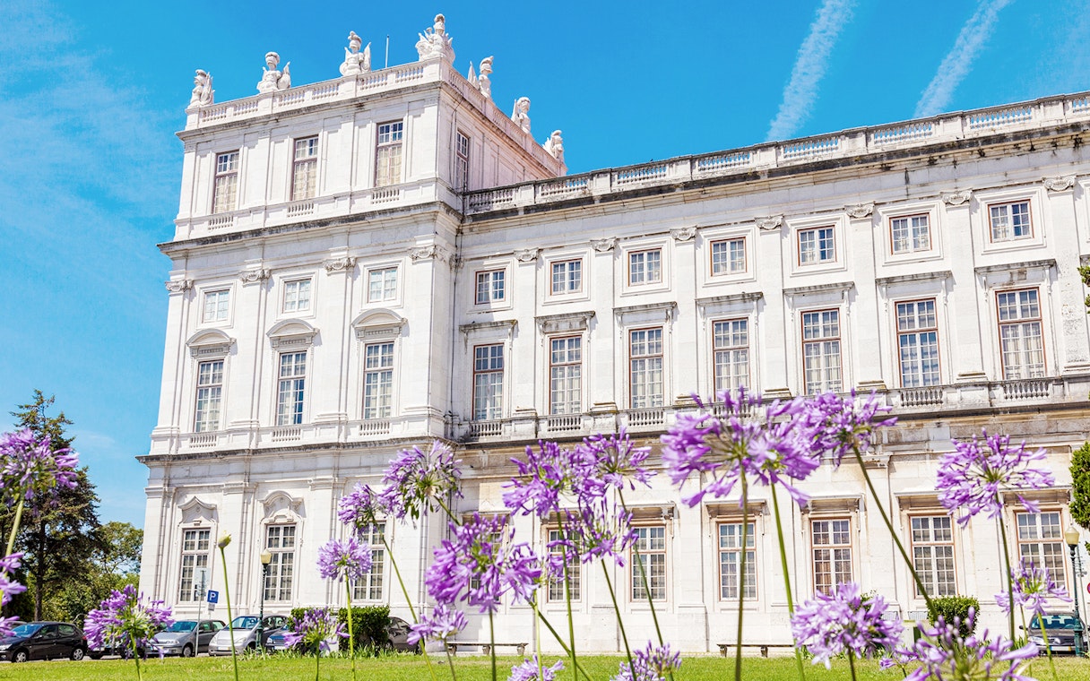 National Palace of Ajuda facade with purple flowers in Lisbon, Portugal.