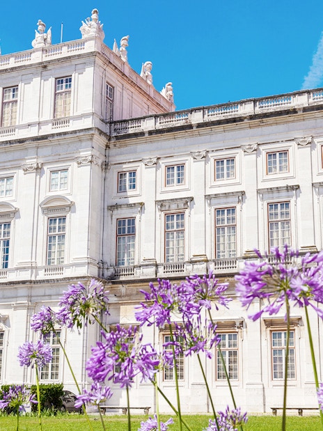 National Palace of Ajuda facade with purple flowers in Lisbon, Portugal.