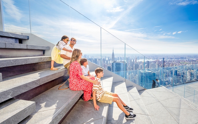 Family enjoying skyline view from Edge observation deck in New York City.
