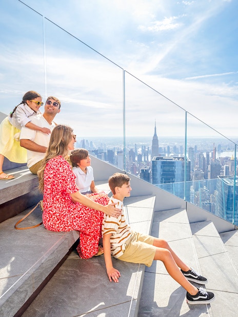 Family enjoying skyline view from Edge observation deck in New York City.