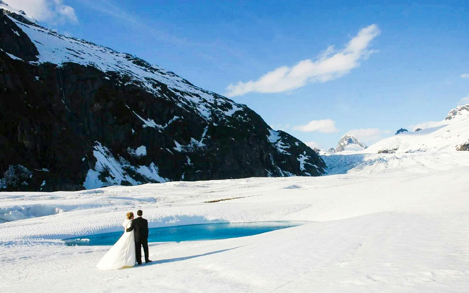 Couple standing on a glacier during Juneau helicopter tour with dog sledding.